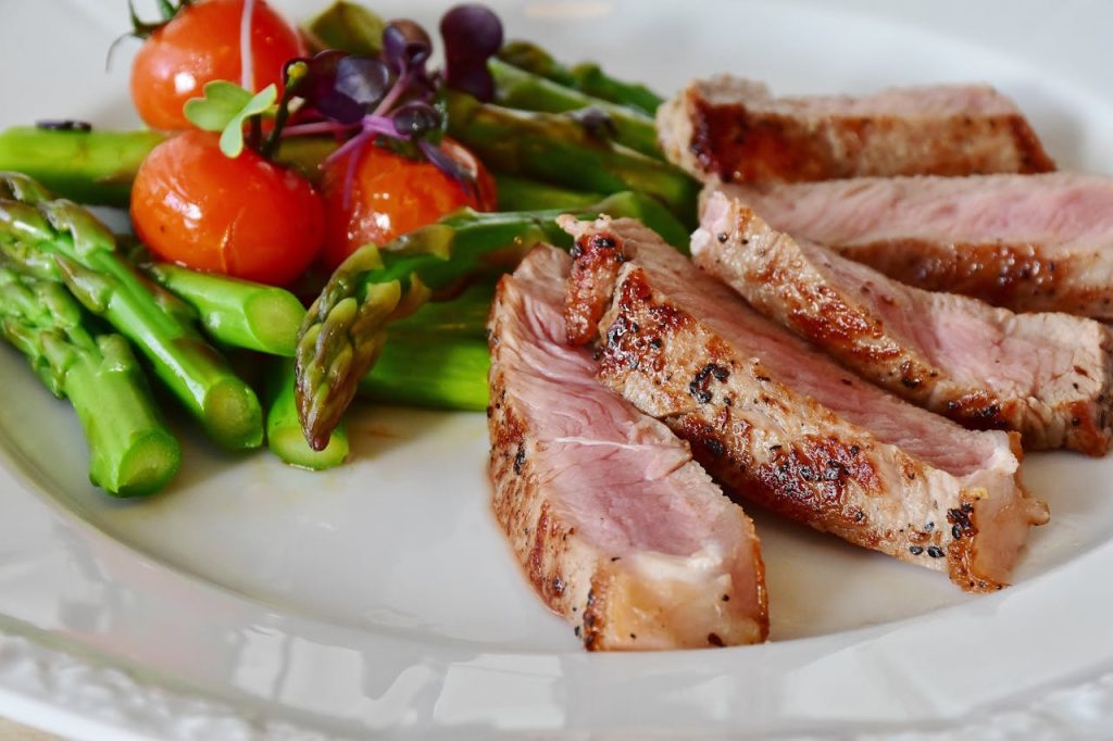 grilled-meat-dish-served-on-white-plate-361184 Close-up of grilled steak slices with asparagus and cherry tomatoes, perfect for a healthy meal.